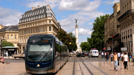 Slow-motion-shot-of-tram-on-city-of-Bordeaux-and-famous-Monument-aux-Girondins-in-background---France,-Europe---Wide-shot