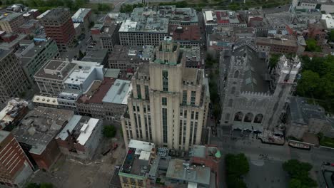 Old-Montreal-4k-drone-aerial-flyover-360-birds-eye-view-summer-day-overlooking-Notre-Dame-church-renovations-fencing-around-the-front-entrance