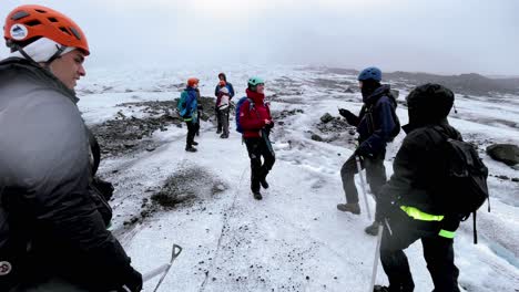 Iceland---Moderate-Glacier-Hike-in-Skaftafell:-A-hiker-walks-across-the-snow-covered-surface-of-Falljökull-glacier,-surrounded-by-towering-mountains