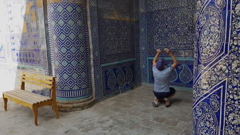 Tourist-Taking-Pictures-of-Mosaic-Walls-in-Courtyard-of-Itchan-Kala,-Old-Walled-City,-Khiva-Uzbekistan