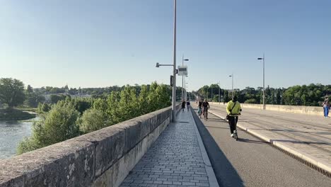 Slow-motion-e-scooter-and-cyclists-on-bridge-Wilson-in-Tours-city,-France