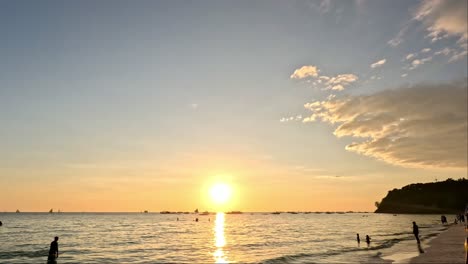 Menschen-Am-Strand-Genießen-Den-Wunderschönen-Sonnenuntergang,-Der-Den-Himmel-Am-Strand-Der-Insel-Boracay,-Philippinen,-Gelb-Und-Orange-Färbt