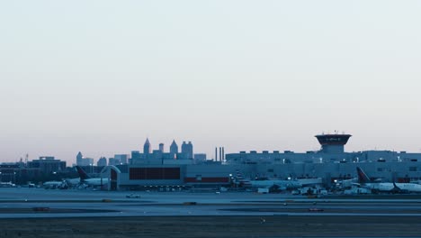 Eine-Totalaufnahme-Von-Delta-Verkehrsflugzeugtaxis-Am-Flughafen-Atlanta-Mit-Der-Skyline-Von-Atlanta,-Georgia-Im-Hintergrund-Am-Morgen