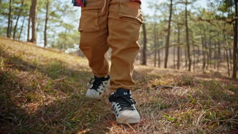 A-boy-with-feet-in-sneakers-walking-along-path-in-the-autumn-forest