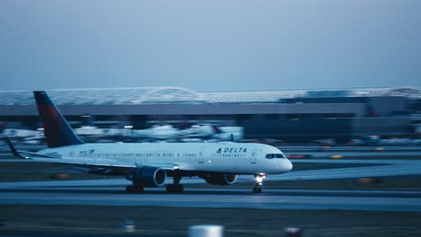 Medium-shot-of-a-Delta-commercial-airplane-landing-on-a-runway-at-ATL-airport-in-Atlanta,-Georgia-in-the-evening