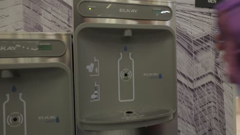 Person,-Die-Die-An-Der-Wand-Montierte-Wasserflaschen-Nachfüllstation-Von-Elkay-Am-JFK-Flughafenterminal-Nutzt