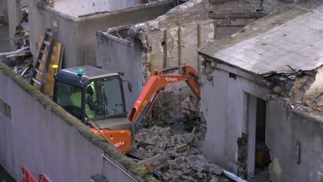 Excavators-breaks-down-brick-wall-building-removes-rubble-and-loads-onto-side