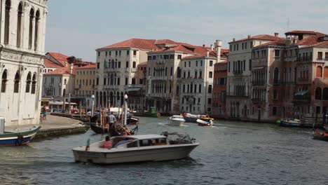 Venetian-boats-riding-through-the-Grand-Canal-in-Venice,-Italy