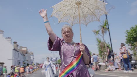 Woman-in-period-costume-walking-in-parade-at-Pride-festival-on-Isle-of-White-2018-as-bubbles-float-around-her