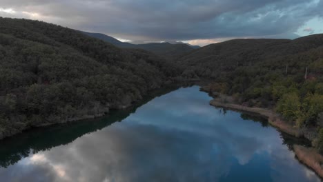 Schnelle-Luftaufnahme-über-Dem-Ruhigen-Wasser-Des-Bergsees,-Das-Den-Sonnenuntergangswolkenwald-Reflektiert