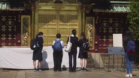 Niños-De-Escuela-En-Uniforme-Diciendo-Una-Oración-Y-Haciendo-Una-Reverencia-Ante-El-Altar-Japonés-En-El-Suburbio-De-Ueno,-Tokio,-Japón