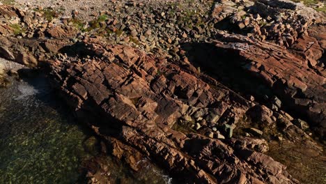 Long-Studio-Isolated-with-Scenic-Joe-Batt's-Arm-Landscape-from-Aerial-Drone-Tilt-Up-Reveal-Along-the-Rocky-Coast-of-Fogo-Island,-Newfoundland,-Canada