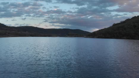 Schnelle-Luftaufnahmen-über-Dem-Bergsee-In-Der-Abenddämmerung.-Der-Sonnenuntergang-Färbt-Violette-Wolken