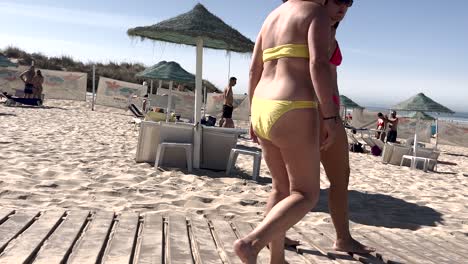 Two-women-relax-on-sun-loungers-before-heading-for-a-swim-on-a-sunny-day-at-Costa-da-Caparica,-embodying-the-leisurely-charm-of-a-beach-day