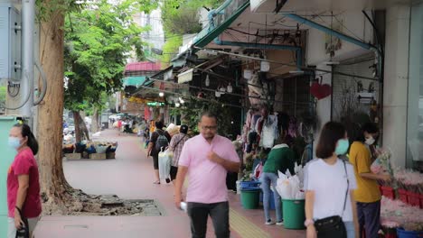 Gente-Caminando-Por-La-Acera-Fuera-De-Las-Tiendas-Del-Mercado-De-Flores-En-Bangkok,-Tailandia