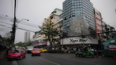 Busy-Vehicle-Traffic-Flowing-Past-Flower-Market-in-Bangkok