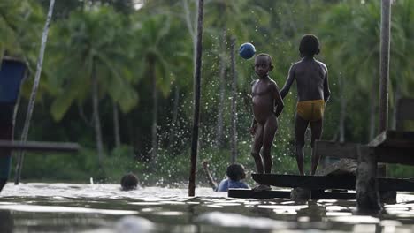 A-group-of-cheerful-children-having-fun-jumping-and-swimming-in-the-river,-Asmat,-Papua,-Indonesia
