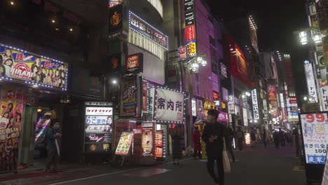 Gente-Caminando-Por-La-Calle-Pasando-Por-Letreros-De-Neón-Parpadeantes-En-Golden-Gai-Shinjuku-Por-La-Noche