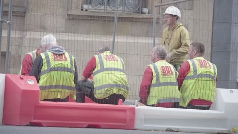 Los-Trabajadores-De-La-Construcción-Del-Centro-De-La-Ciudad-De-Glasgow-Toman-Un-Descanso-Mientras-La-Gente-Pasa