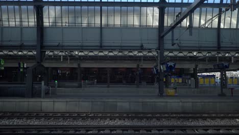 Woman-walking-on-an-empty-platform-at-the-central-train-station-during-covid19-lockdown,-Noord-Holland,-Amstersam,-Netherlands