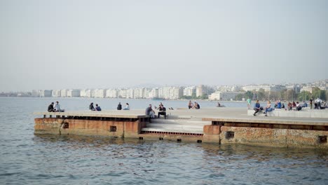 Junge-Leute-Sitzen-Am-Pier-Und-Entspannen-Sich-Am-Meer.-Thessaloniki,-Neue-Promenade,-Sommertag
