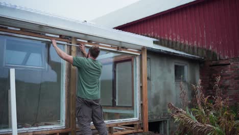 Builder-With-Foldable-Meter-Stick-Is-Measuring-Clearance-Of-Greenhouse-Windows