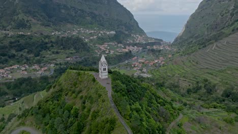 Bird's-eye-view-above-tower-church-in-Madeira-Portugal-overlooking-valley-and-sea
