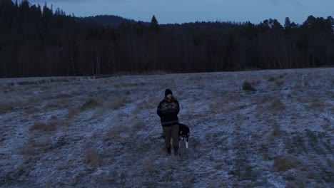 Indre-Fosen,-Kreis-Tröndelag,-Norwegen-–-Ein-Mann-Spaziert-Im-November-Mit-Seinem-Hund-über-Den-Bauernhof-–-Kamerafahrt