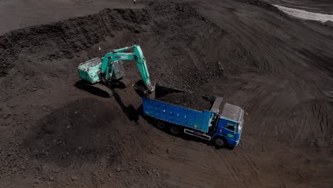 Aerial-view-of-excavator-load-crushed-coal-into-dump-truck-at-open-pit-site