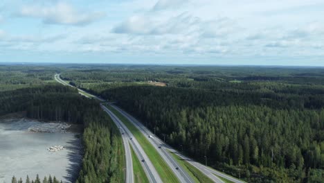 Aéreo:-El-Tráfico-De-Automóviles-Circula-Por-Una-Carretera-Dividida-A-Través-Del-Bosque-Finlandés