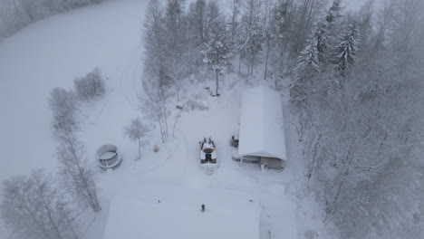 Aerial-circle-view-of-tractor-plows-snow-in-a-home-backyard