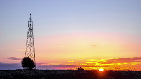 Sun-rising-in-horizon-with-silhouette-of-communication-tower-in-foreground