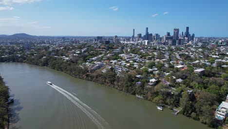 Boat-Cruising-On-Brisbane-River-With-Distant-View-Of-City-Skyline-In-Queensland,-Australia