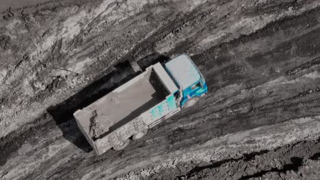 Dirty-dump-truck-carry-liquid-mud-as-cargo-on-dark-dirt-coal-mine-road
