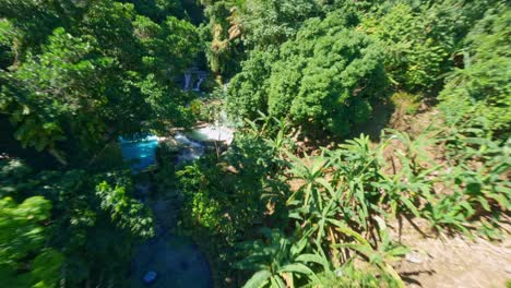 Fpv-flight-over-waterfall-,-River-and-Villa-Miriam-in-Barahona-during-sunny-day,-Dominican-Republic