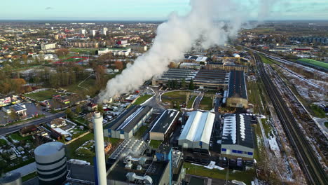Aerial-view-of-a-smoking-factory-chimney,-urban-city-background,-sunny-fall-day