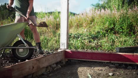 Person-Shoveling-Soil-From-Wheelbarrow-In-The-Backyard
