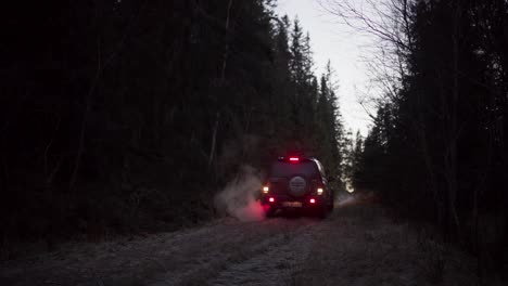 SUV's-Backside-Billows-Smoke-From-Its-Exhaust-Pipe-As-It-Reverses-Along-Rural-Trail-At-Sunset