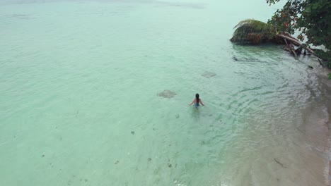 A-girl-in-a-bikini-walks-on-Zapatilla-Cay-beach-in-Bocas-del-Toro,-Panama