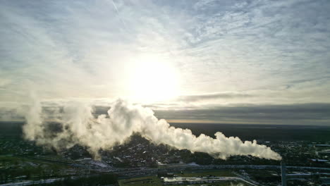 Steam-coming-from-a-smokestack-at-a-district-heating-complex---aerial-view-at-sunset