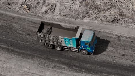 Aerial-view-of-lorry-with-liquid-dirt-cargo-drive-on-dark-coal-mine-road