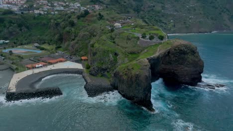 Aerial-pullback-from-Guindaste-viewpoint-in-Madeira-Portugal,-secluded-cove-and-cliff