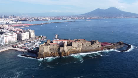 Castel-dell'Ovo-Seafront-Egg-Castle,-Naples-with-Mount-Vesuvius-AERIAL