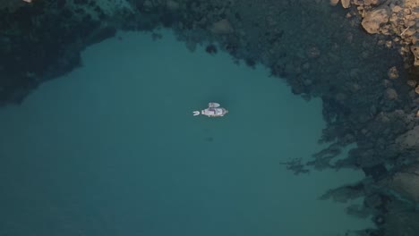 Drohne-Von-Oben-Nach-Unten-Erhebt-Sich-über-Boot-Mit-Beiboot-Und-Floß-Im-Türkisgrünen-Sandwasser