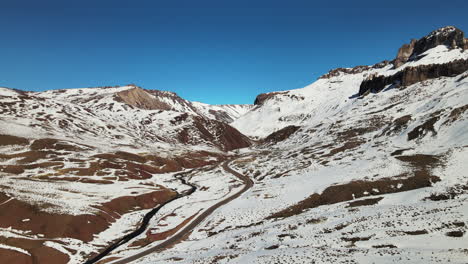 Wunderschönes-Drohnenbild-Der-Route,-Die-Zum-Verschneiten-Tal-Von-Las-Leñas-Führt-Und-Die-Atemberaubende-Schönheit-Der-Reise-Inmitten-Der-Andenlandschaften-Einfängt