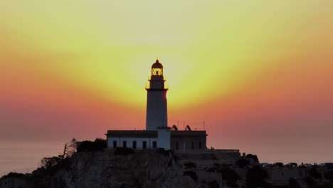 Backlit-stunning-silhouette-of-lighthouse-with-epic-red-yellow-sunrise-glowing-haze-spouting-from-tower