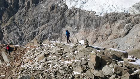 Explorador-Caminando-Por-El-Borde-Nevado-De-La-Cima-De-La-Montaña-Con-Impresionantes-Vistas-De-La-Cordillera-De-Los-Alpes-Al-Fondo,-Cima-Fontana,-Valmalenco-En-Italia