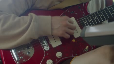 Close-up:-Man-plays-red-Fender-Jaguar-guitar-with-electric-pickups