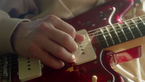 Closeup-view-of-hand-picking-classic-red-Fender-Jaguar-electric-guitar