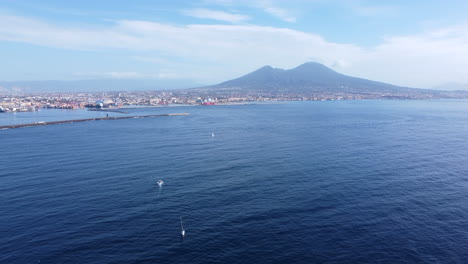 Aerial-tilt-up-of-coast-of-Naples,-Mount-Vesuvius-in-background,-Italy